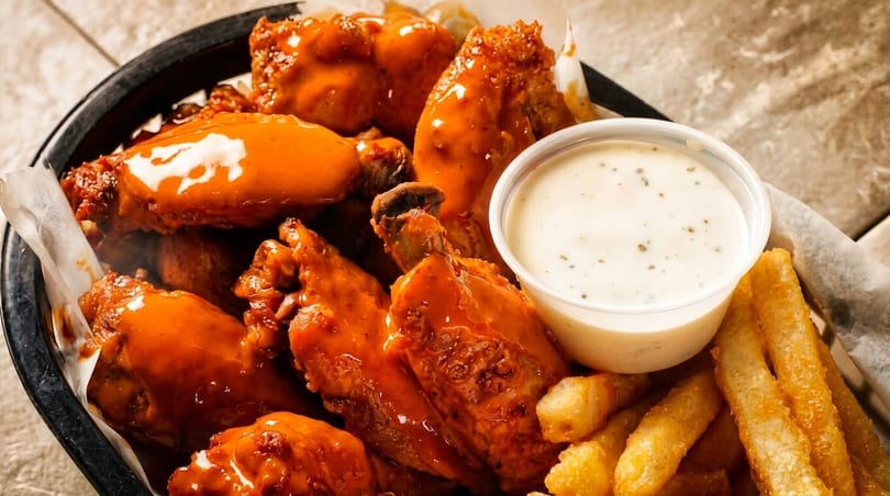 A basket of buffalo chicken wings, french fries, and a side of ranch dressing.
